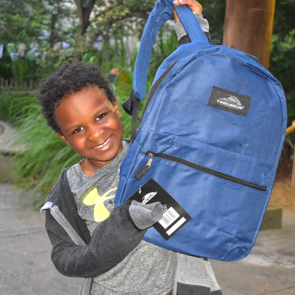 Boy smiling while holding up backpack