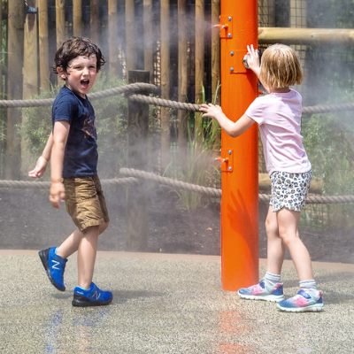 Boy and girl playing in misters